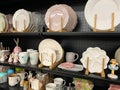 Ceramic plates and cups, on the black shelf of the store.