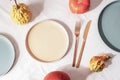 Ceramic plates with fork and knife and pumpkins serving background on white tablecloth. Top view, mockup