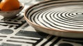 A ceramic platter adorned with a minimalist black and white pattern of inter lines.