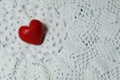 Ceramic red heart on white lace knitted fabric. Crochet Favorite hobby, Valentine. Royalty Free Stock Photo