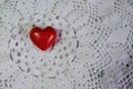 Ceramic red heart on white lace knitted fabric. Crochet Favorite hobby, Valentine. Royalty Free Stock Photo