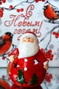 Ceramic santa claus figurine on background of the inscription in Russian designating happy new year