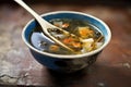 ceramic spoon resting in a bowl of hot and sour soup