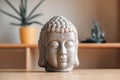 Ceramic statuette of a Buddha head on a wooden shelf. Copy, empty space for text