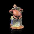 Ceramic statuette of a fat man on a black background. Royalty Free Stock Photo