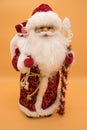 Ceramic statuette of Santa Claus in a red coat holding a staff isolated on yellow background Royalty Free Stock Photo