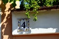 Ceramic street number plate on stucco wall. green grape vine closeup Royalty Free Stock Photo