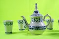 Ceramic teapot and cup on the green background