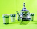 Ceramic teapot and cup on the green background