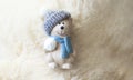 Ceramic teddy bear in a cap on a white fluffy background