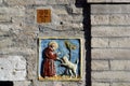 Ceramic tile set into a wall showing Saint Francis befriending a wolf, Assisi, Italy