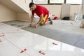 Ceramic white floor tiles laid over adhesive with a tile leveling system