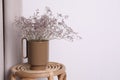 Ceramic vase with dry flowers on wicker table near white wall. Space for text Royalty Free Stock Photo