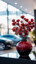 Ceramic vase holds fake red flowers on a glass table, showroom elegance.
