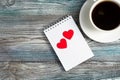 Ceramic white coffee mug and two red hearts on a Notepad. Royalty Free Stock Photo