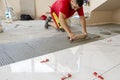 Ceramic white floor tiles laid over adhesive with a tile leveling system