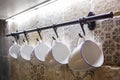 Ceramic white mugs hanging on hooks in the kitchen Royalty Free Stock Photo