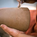 Ceramic workshop, the master puts otnament on unfired earthenware jug. Close-up of master hands. Made by hand, a hobby. Background