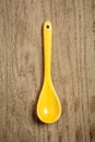 Ceramic yellow spoon over wooden background