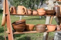 Ceramics fair in Park. Clay dishes on wooden shelf. Pottery craft. Kitchen utensils. Folk art. Everyday life. Household goods