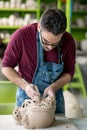 Ceramist Dressed in an Apron Sculpting Statue from Raw Clay in Bright Ceramic Workshop. Royalty Free Stock Photo