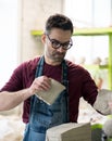 Ceramist Dressed in an Apron Working with Raw Clay in Bright Ceramic Workshop. Royalty Free Stock Photo