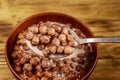 Cereal chocolate balls with milk in a bowl on wooden table. Spoon with breakfast Royalty Free Stock Photo