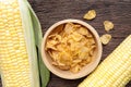 Cereal corn flakes in wooden bowl and corncobs on wooden table. Royalty Free Stock Photo