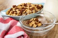 Cereal breakfast with chocolate and caramel in blue bowl, napkin, spoon with cereal in bowl on wooden table