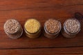 Cereal grains in glass jars on wooden background. Collection of different groats top view barley, oats, millet and wheat