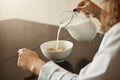 Cereals is best breakfast to keep fit. Cropped shot of woman sitting in nightwear pouring milk in bowl with cereals Royalty Free Stock Photo