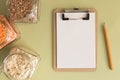 Cereals in glass jars on the table next to a Notepad and pencil. Space for text, white sheet of paper.