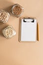 Cereals in glass jars on the table next to a Notepad and pencil. Space for text, white sheet of paper.