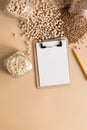 Cereals in glass jars on the table next to a Notepad and pencil. Space for text, white sheet of paper.