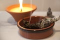 Ceremonial White Sage Smudge Stick burning with a candle flame burning in the background Royalty Free Stock Photo