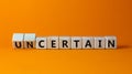 Certain or uncertain symbol. Turned wooden cubes and changed the concept word uncertain to certain. Beautiful orange table, orange Royalty Free Stock Photo