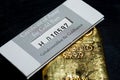 The certificate of assay for gold bars lies on a cast gold ingot. Royalty Free Stock Photo