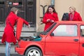 Three women in red clothes at a red vintage car Fiat 126 with an open boot