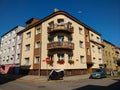 A beige corner apartment building with balcony and red flowers in the basement