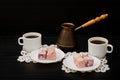 Cezve, colorful Turkish Delight and two cups of coffee on the lace napkins black background Royalty Free Stock Photo