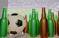 CGI 3D still life design of group of beer bottles , football and TV remote on table in front of big television LCD screen in Royalty Free Stock Photo