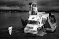 Black and white photograph of a transport truck descending from the ferry in the Chacao canal. Chile