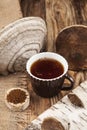 Chaga mushrooms infusion in cup on rustic wooden table. Healthy beverage. View from above. Vertical format