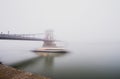 Chain Bridge over the Danube and a boat, Budapest, Hungary, in fog, evening lights Royalty Free Stock Photo