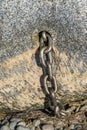 Chain emerging from boulder on beach