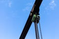 Chain fall hoist tracking on a rusty I beam girder isolated against a brilliant blue sky Royalty Free Stock Photo