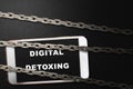 Chain fence locking smartphone with Digital Detoxing text on the screen