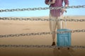 Chain fence with a man with a backpack and suitcase on the desert