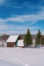 Chain of footprints on white snow leading to a wooden house behind a fence in a mountain valley Royalty Free Stock Photo