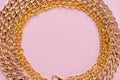 A gold chain laid out in the shape of a heart on a pink background Royalty Free Stock Photo